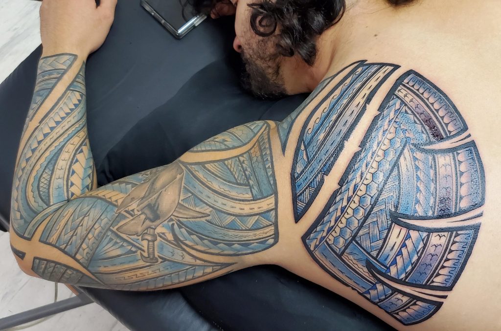 Create a tribal tattoo design that combines elements from Polynesian and  Maori culture. Use symmetrical patterns and geometric shapes to represent  strength and courage. Add natural elements such as waves